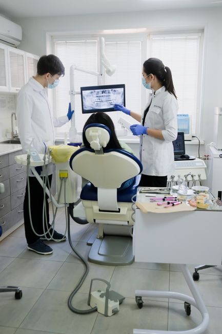 Professional dental team examining patient with advanced equipment in a modern clinic. 12